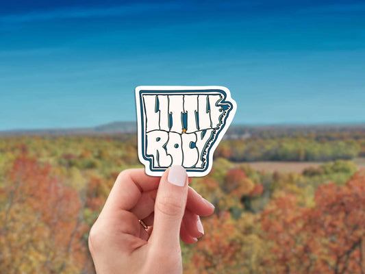 little rock travel luggage sticker, hand display, field landscape background