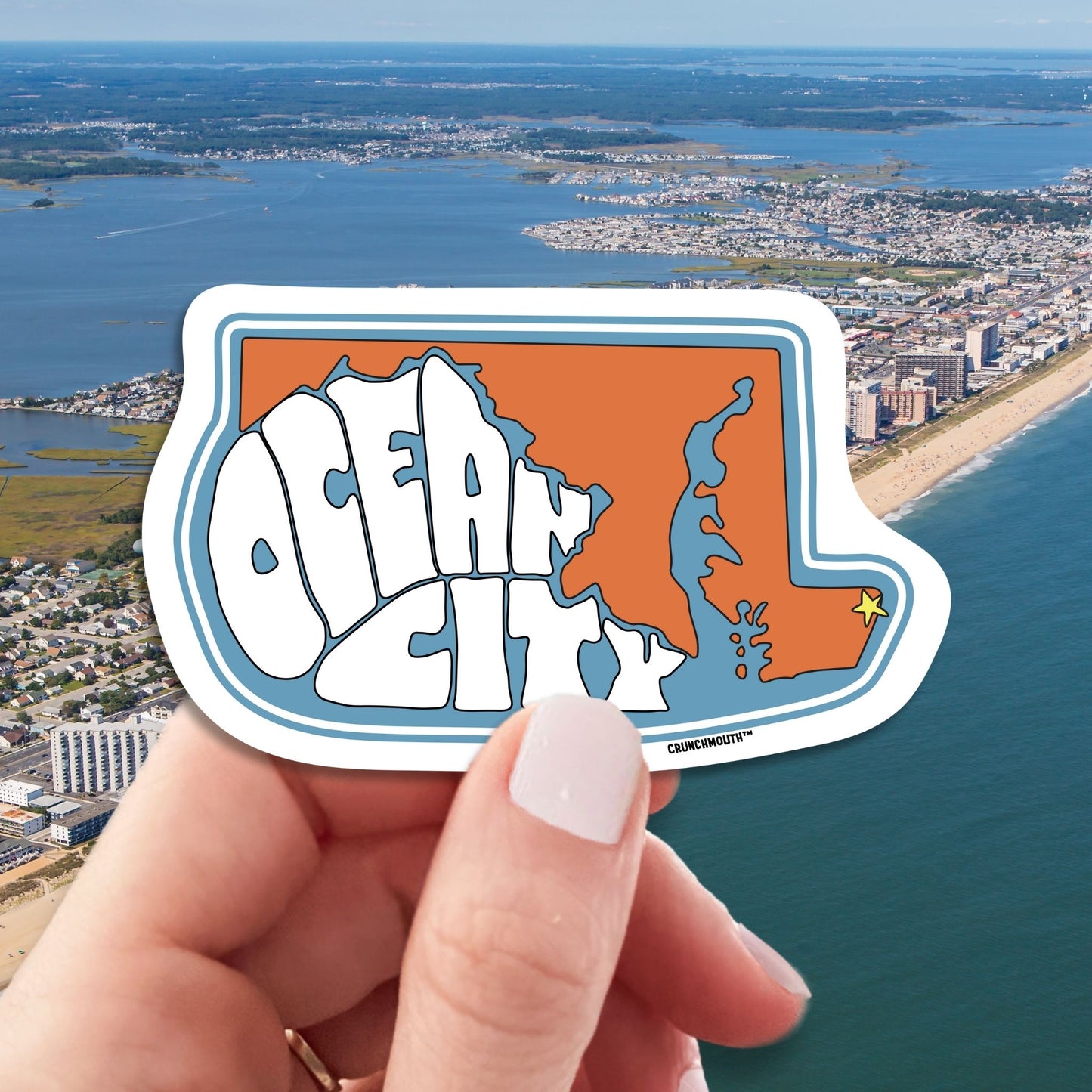 ocean city maryland travel luggage sticker, hand display, aerial cityscape beach background