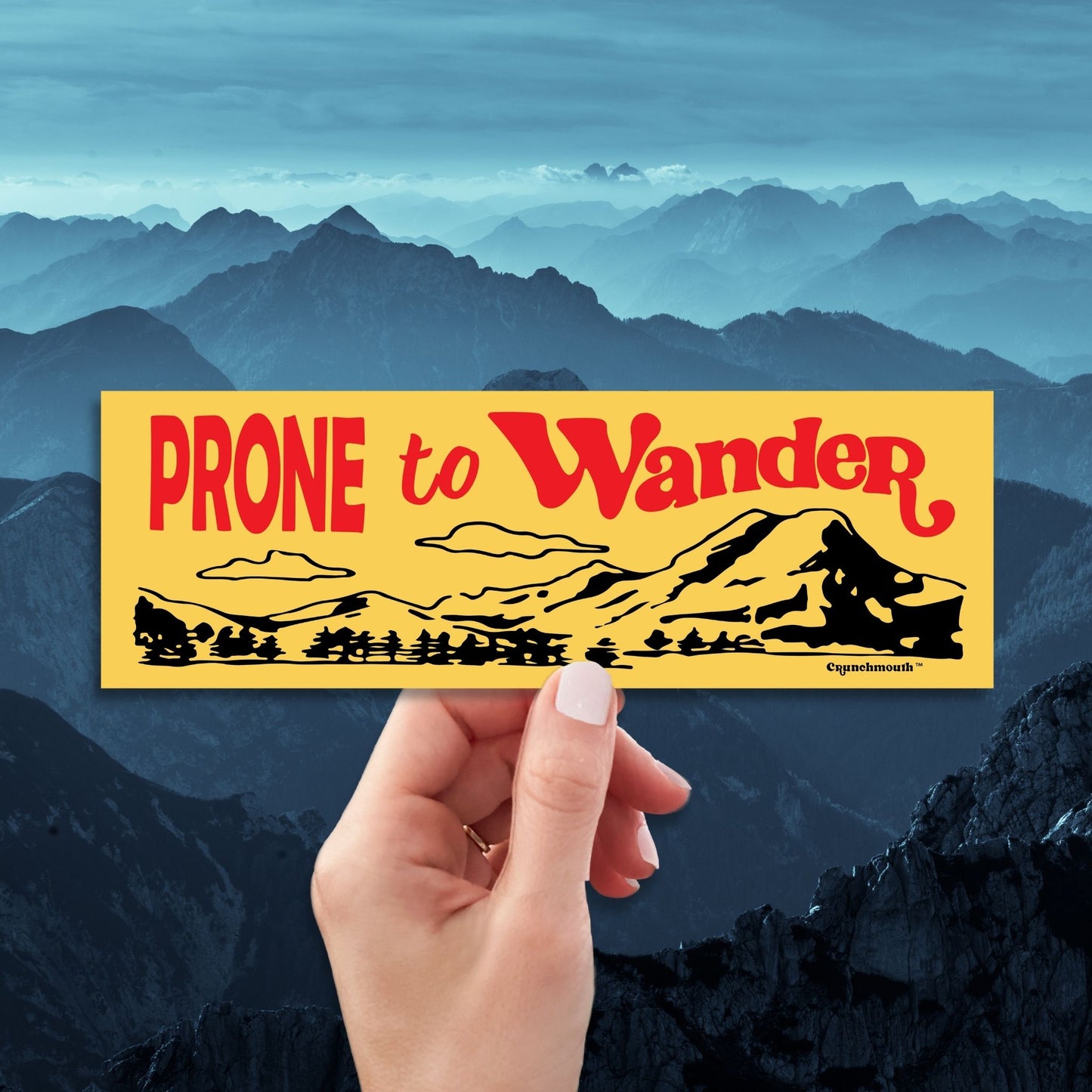 prone to wander bumper sticker, yellow color, hand display, mountains design background