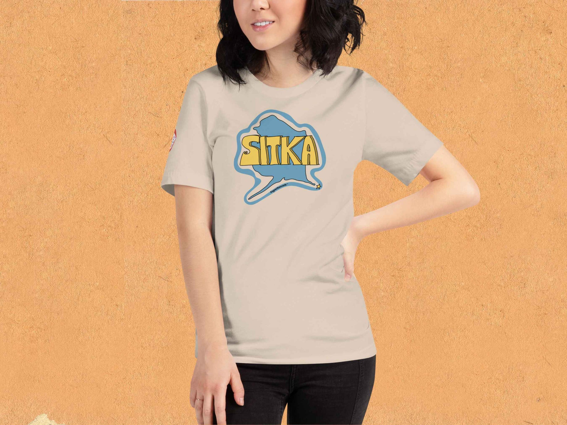 sitka shirt, souvenir t shirts, female model, front, orange textured background