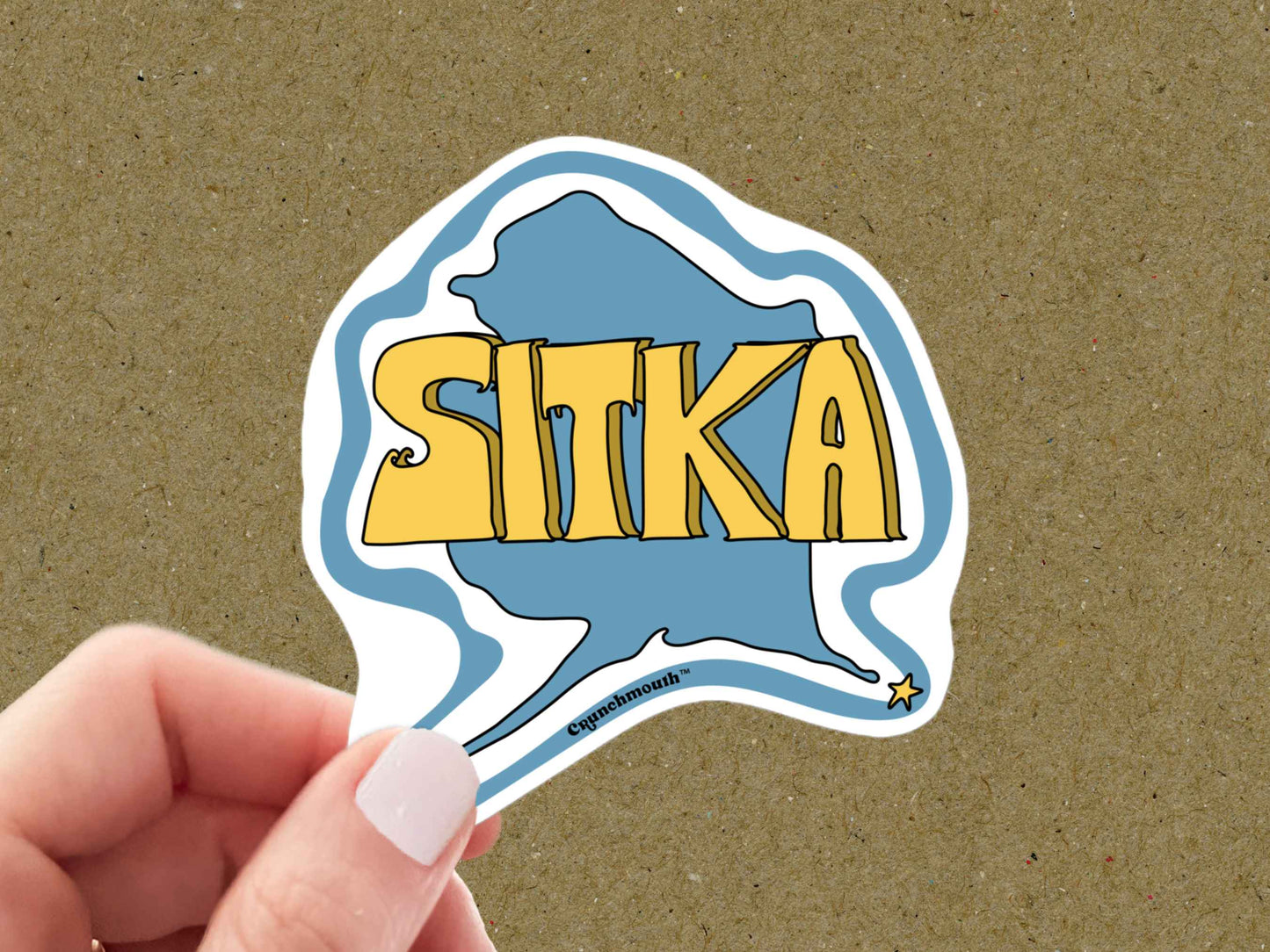 sitka sticker, travel luggage stickers, hand display, brown textured background