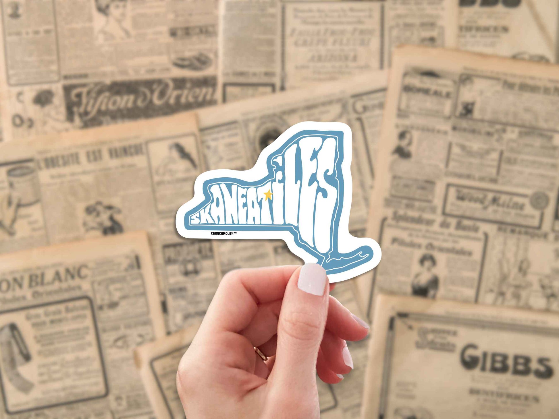 skaneateles travel luggage sticker, hand display, antique newspaper ads background