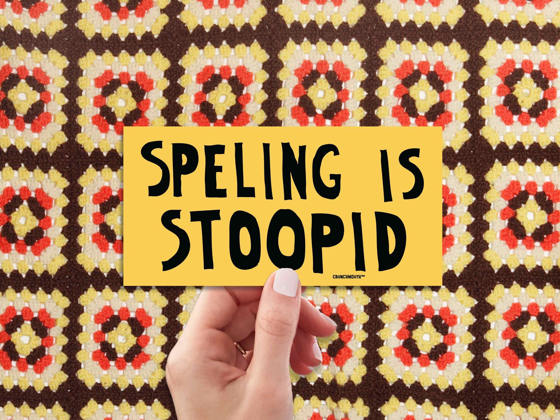 spelling is stupid funny bumper sticker, hand display, 1970s crochet pattern background