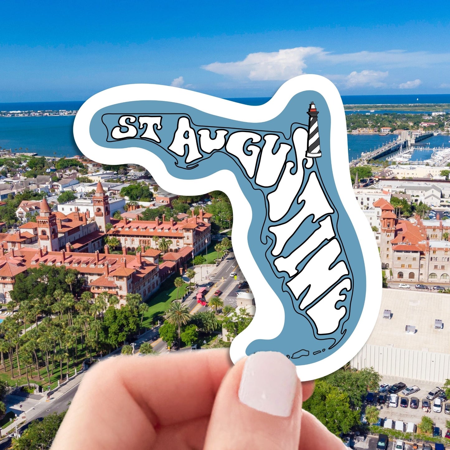 st augustine travel luggage sticker, hand display, aerial cityscape background