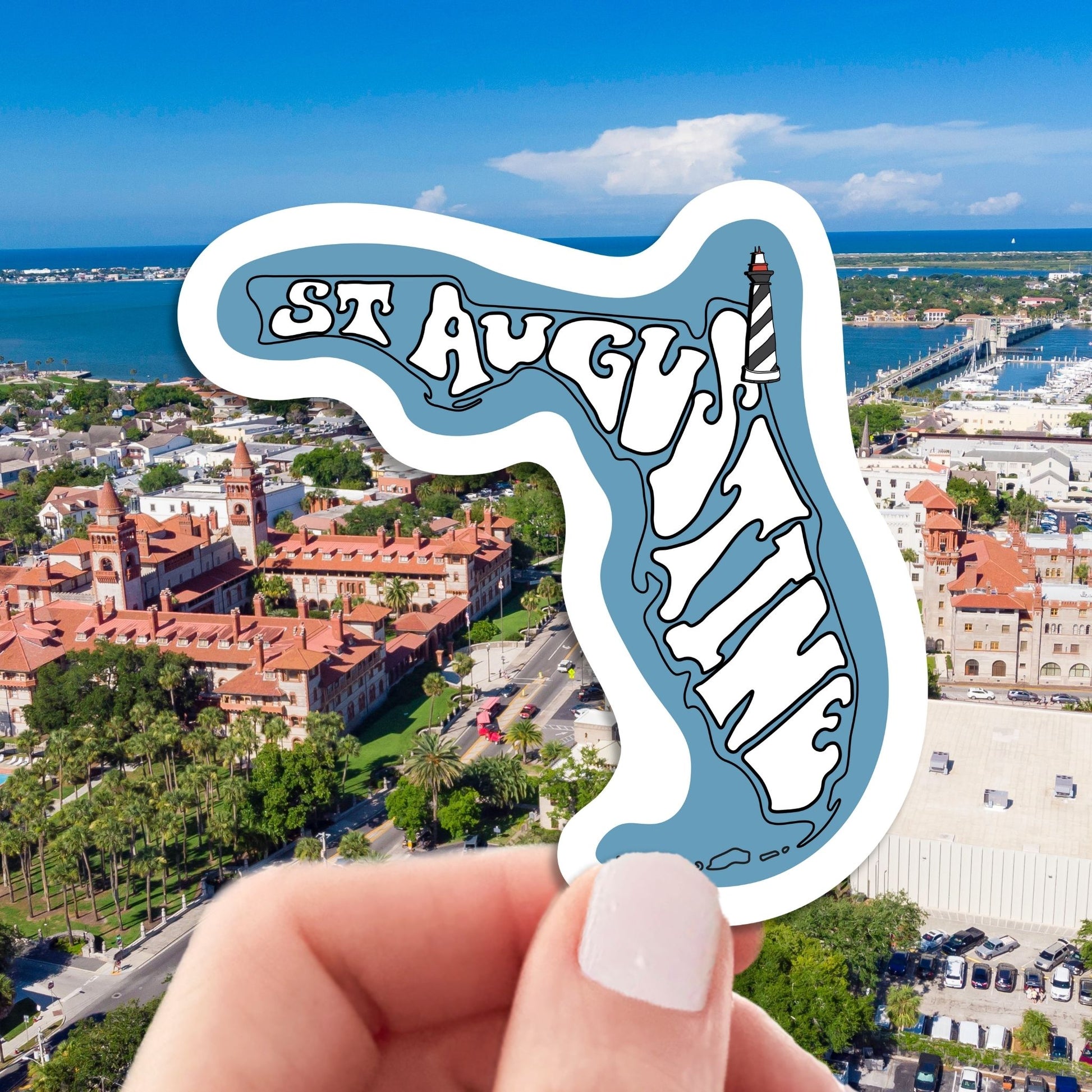 st augustine travel luggage sticker, hand display, aerial cityscape background