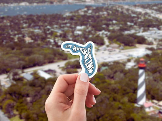 st augustine travel luggage sticker, hand display, lighthouse landscape background