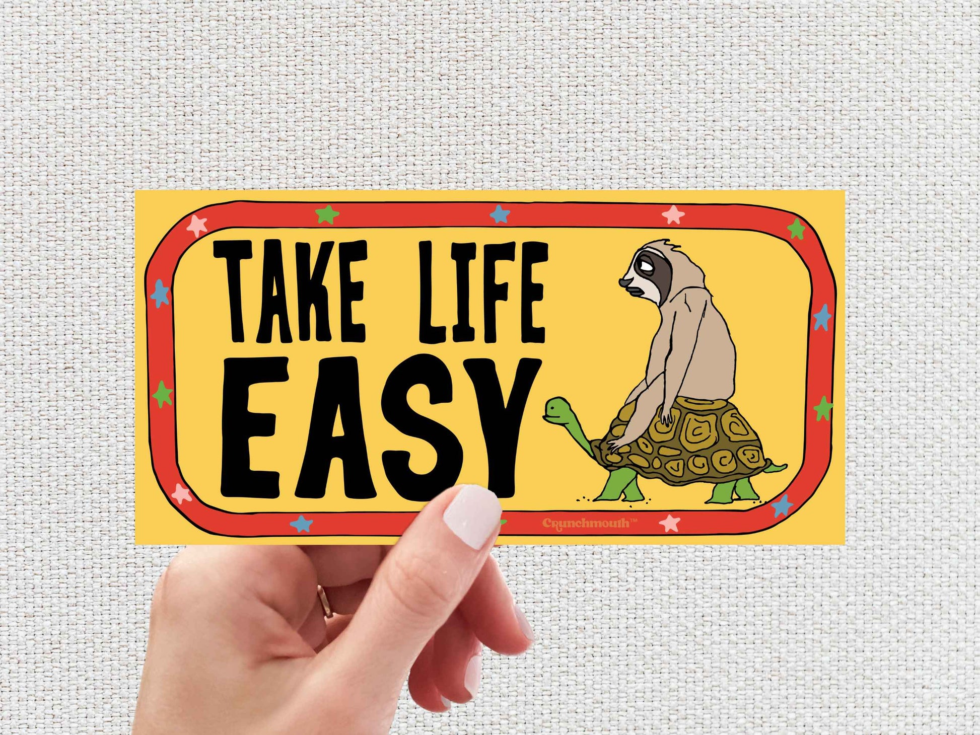 take life easy bumper sticker, hand display, white textured background