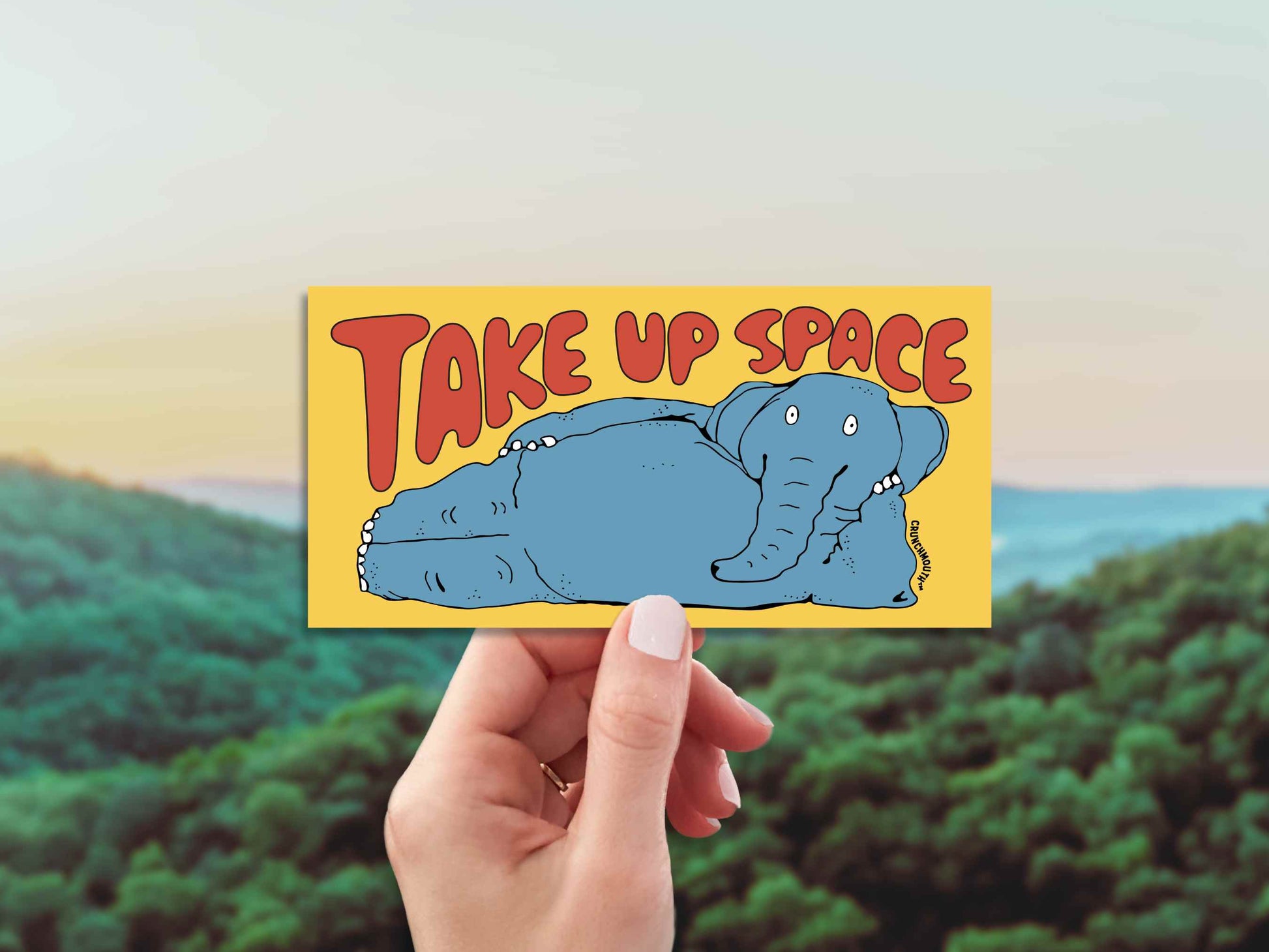 take up space elephant bumper sticker, hand display, green mountains sky background