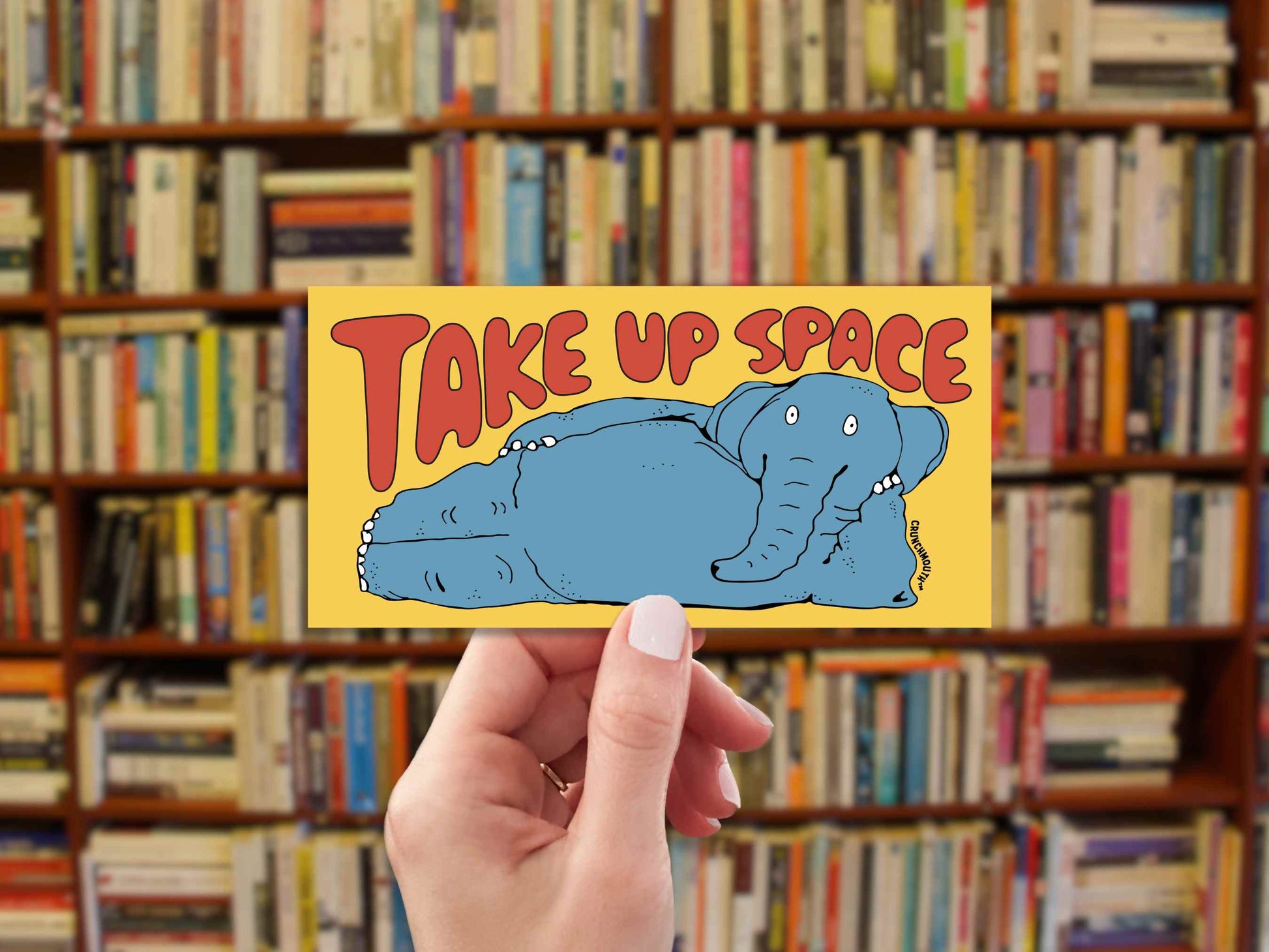 take up space elephant bumper sticker, hand display, bookshelf background
