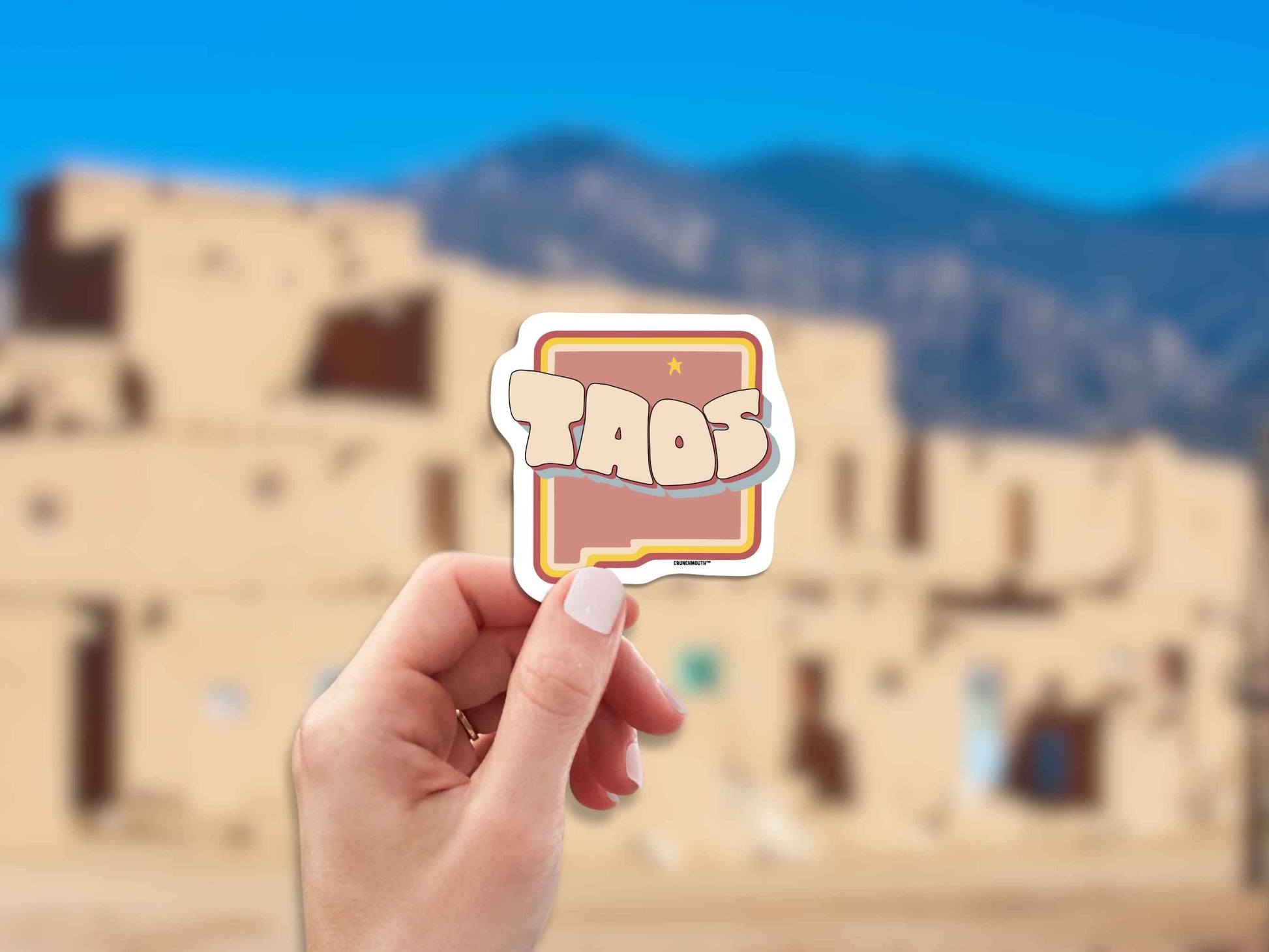taos travel luggage sticker, hand display, blurred landscape background