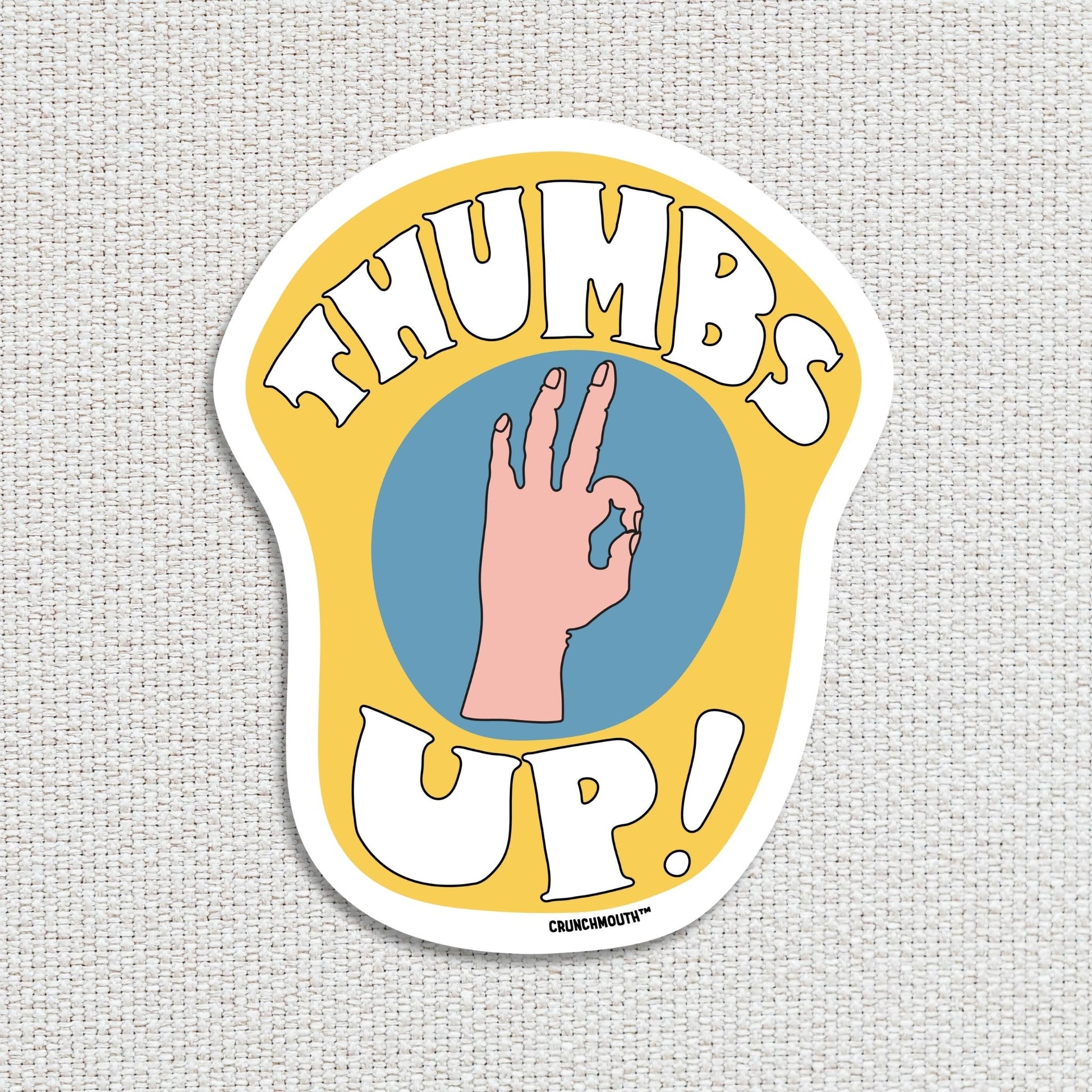 thumbs up a-okay sticker, textured fabric background
