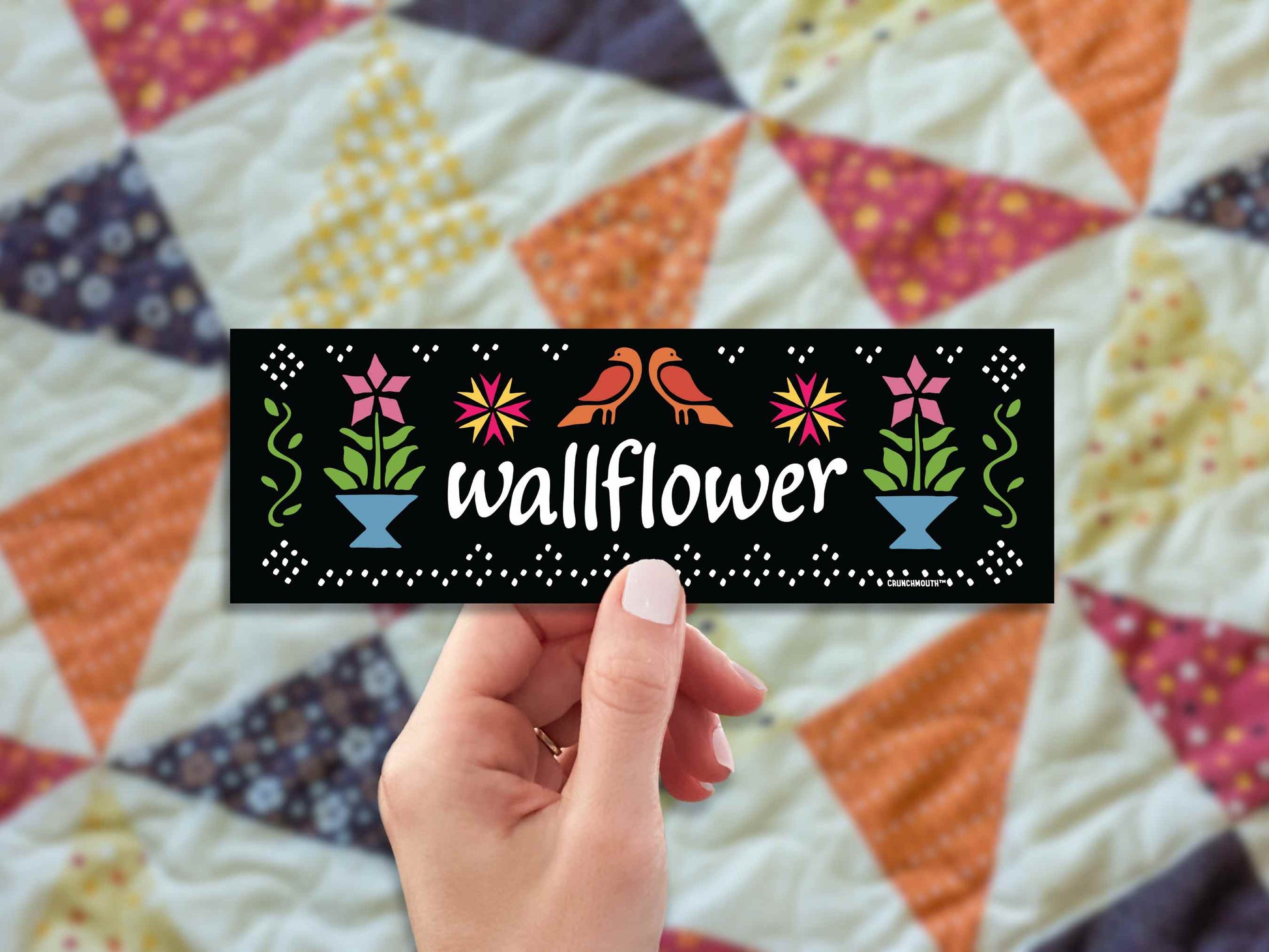 wallflower bumper sticker, hand display, patchwork quilt background