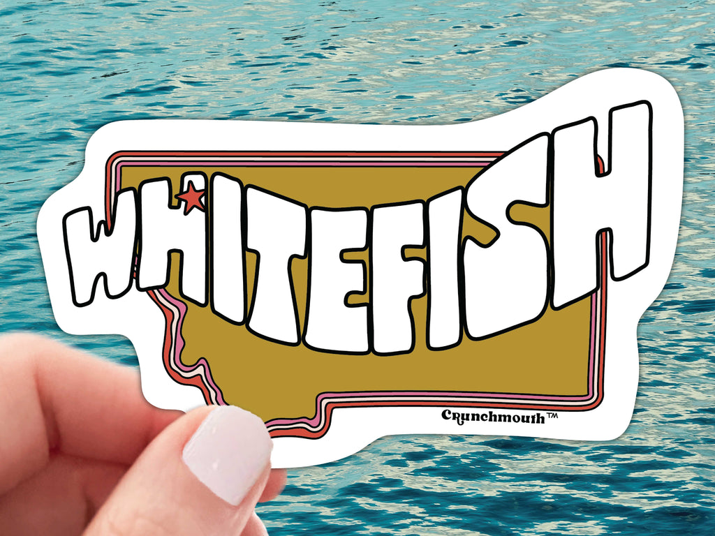 whitefish mt waterproof vinyl sticker, held by hand, water background