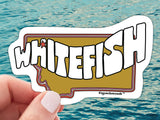 whitefish mt waterproof vinyl sticker, held by hand, water background